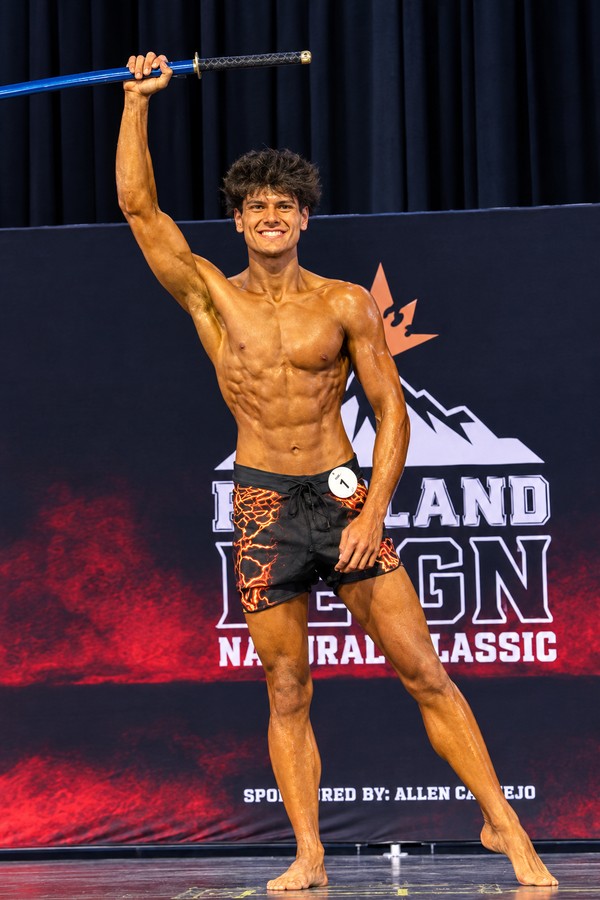 Logan on stage in board shorts at the Portland Reign Natural Classic