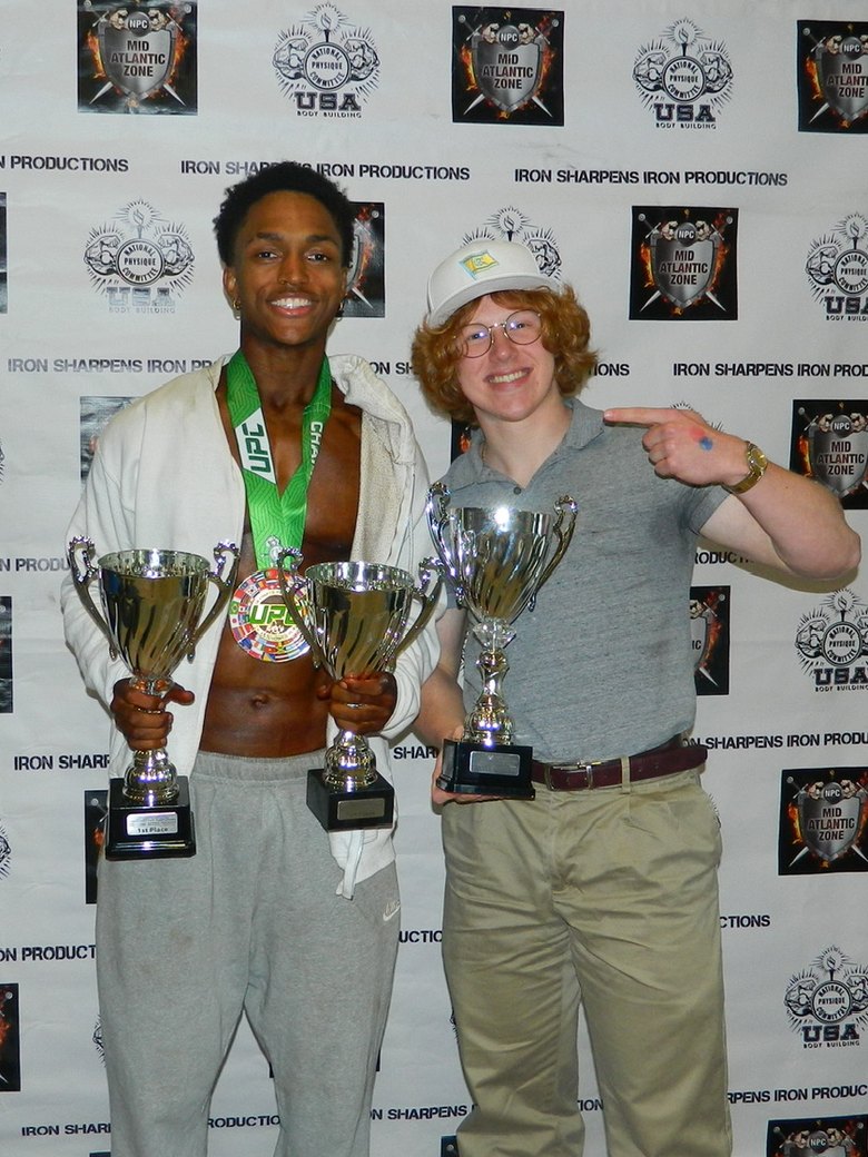 Trenton Laskey with client Milton holding his first place trophies at an NPC show